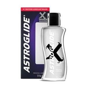 Astroglide Silicone Lubricant bottle on a soft surface with a background of sensual items.